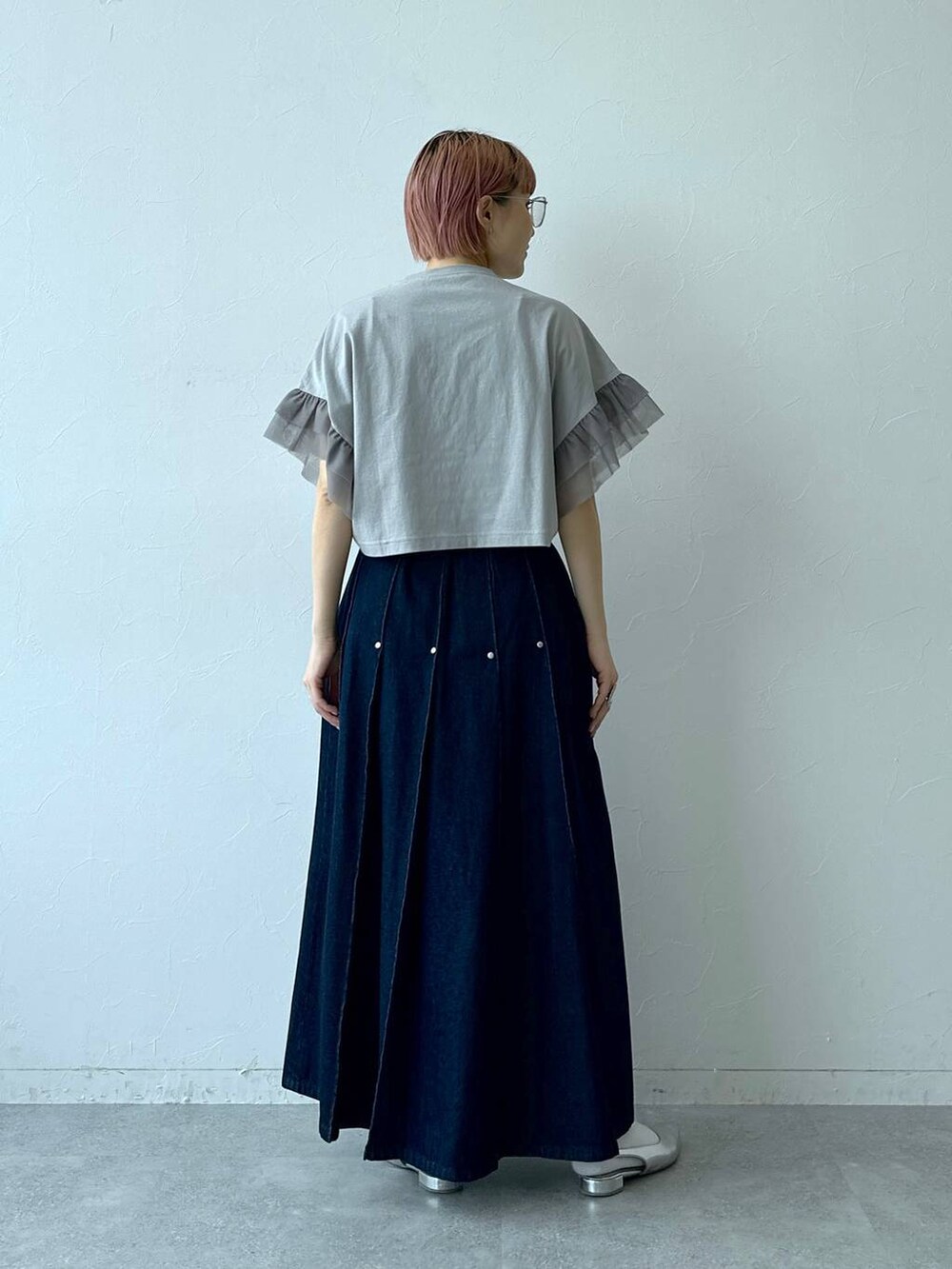 ブルー系のデニムスカート、グレー系のTシャツ/カットソー、ブラック系のメガネを着用したレディースの春コーディネートの6枚目の写真