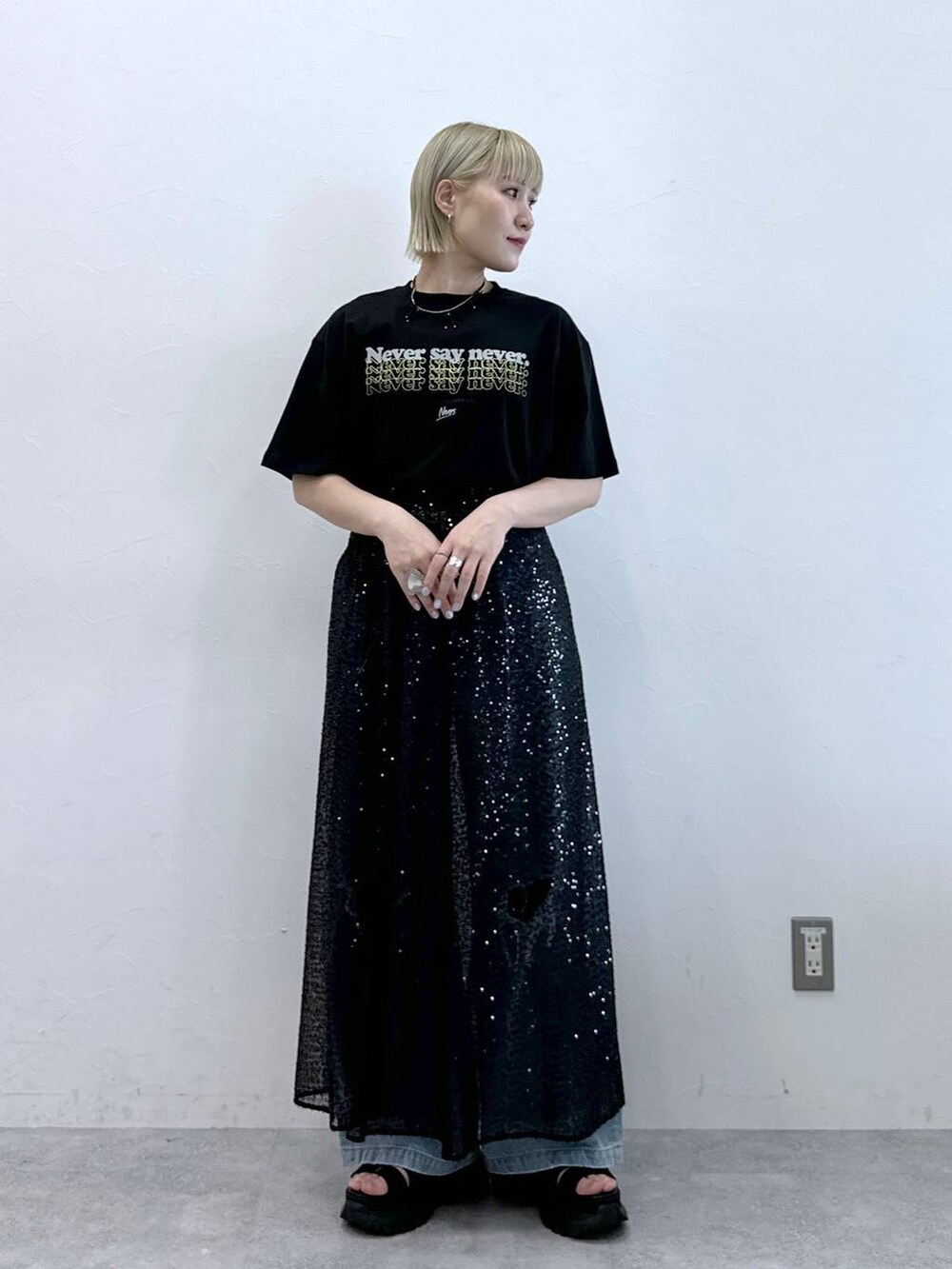 ブルー系のデニムパンツ、ブラック系のサンダル、ブラック系のTシャツ/カットソーを着用したレディースの夏コーディネートの2枚目の写真