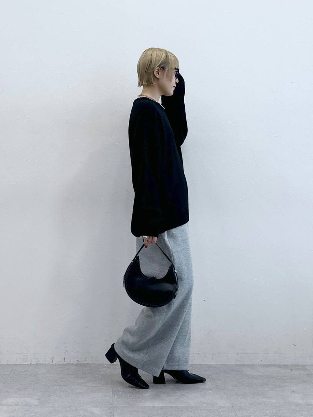 ブラック系のニット/セーター、グレー系のスウェットパンツ、グレー系のメガネを着用したレディースの秋コーディネートの4枚目の写真