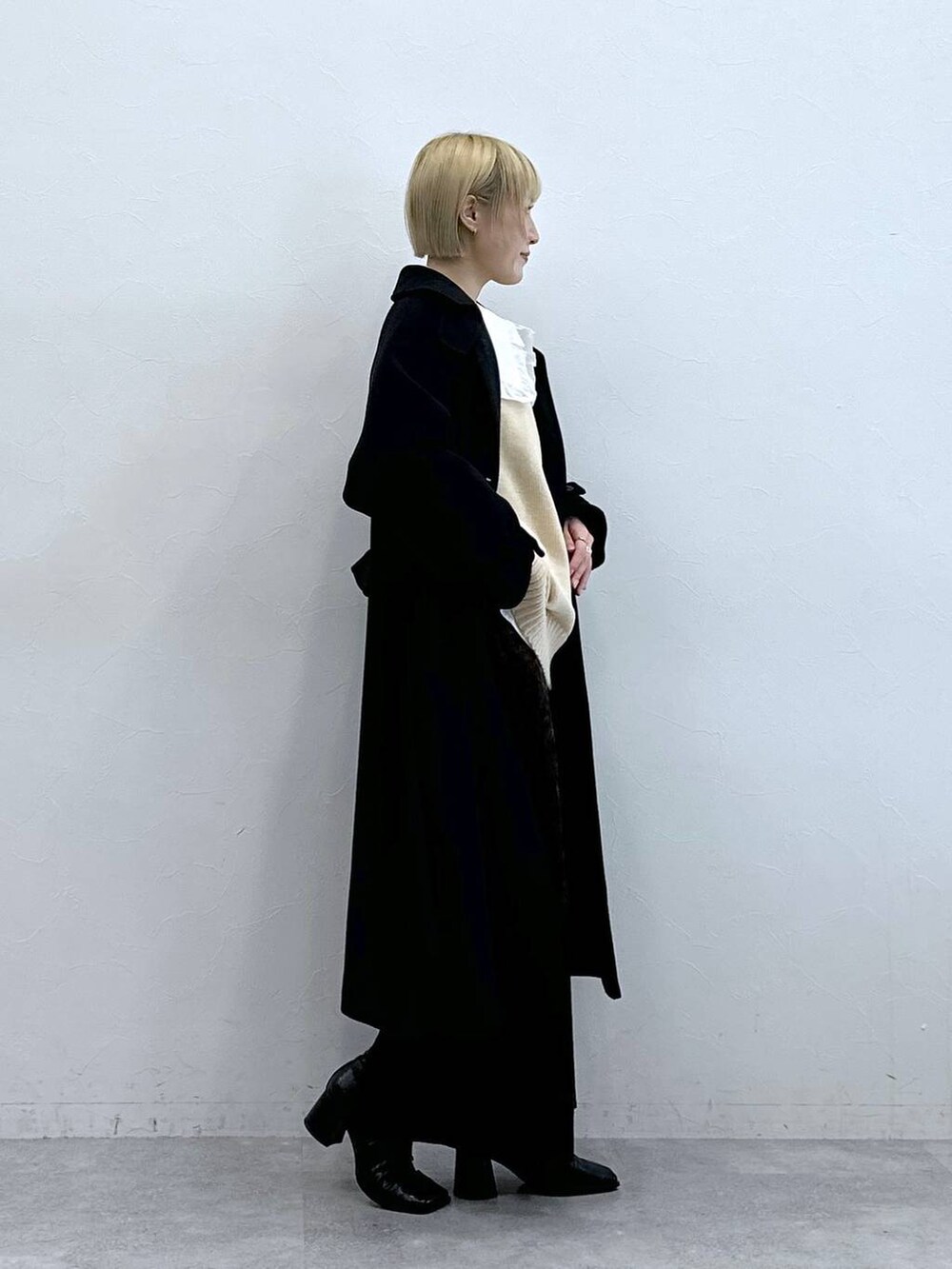 ブラック系のステンカラーコート、ホワイト系のTシャツ/カットソー、ブラック系のスカートを着用したレディースの秋コーディネートの4枚目の写真