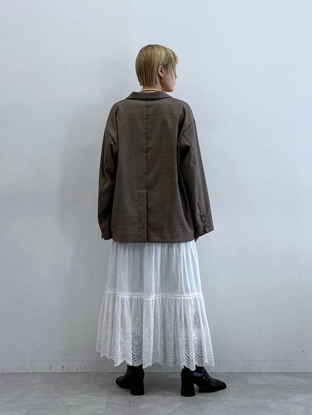 ブラウン系のテーラードジャケット、ホワイト系のスカート、ブラック系のブラジャーを着用したレディースの秋コーディネートの5枚目の写真