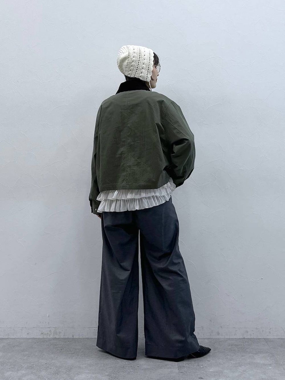 ホワイト系のキャミソール、グリーン系のブルゾン、グレー系のスラックスを着用したレディースの春コーディネートの6枚目の写真