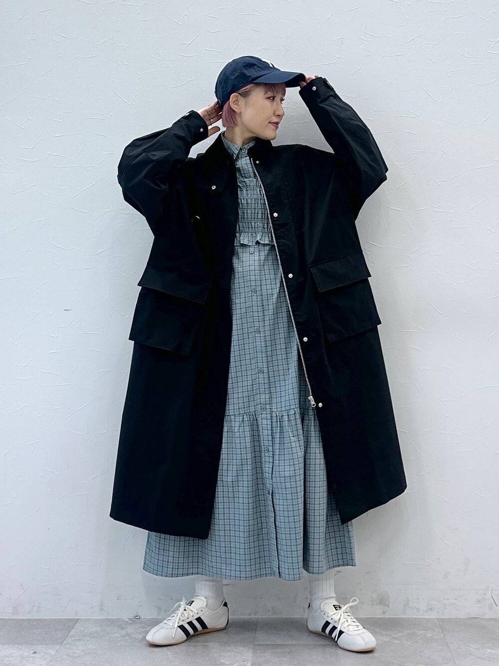 ブラック系のステンカラーコート、ホワイト系のスニーカー、ブルー系のシャツワンピースを着用したレディースの冬コーディネートの6枚目の写真