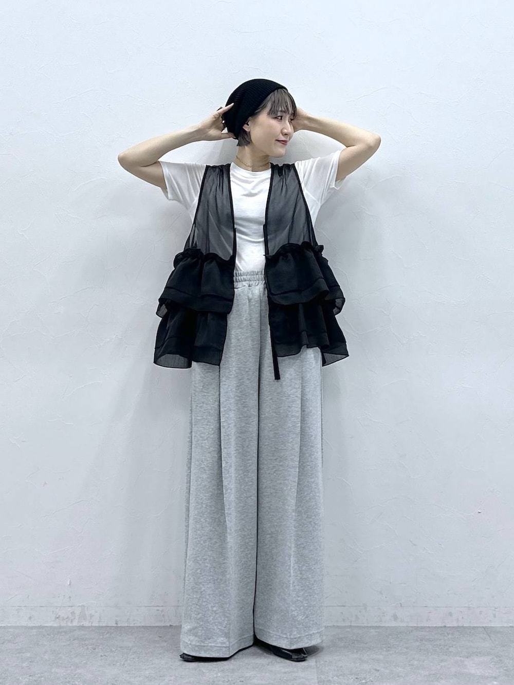 グレー系のスウェットパンツ、ホワイト系のTシャツ/カットソー、ブラック系のベストを着用したレディースの春コーディネートの2枚目の写真