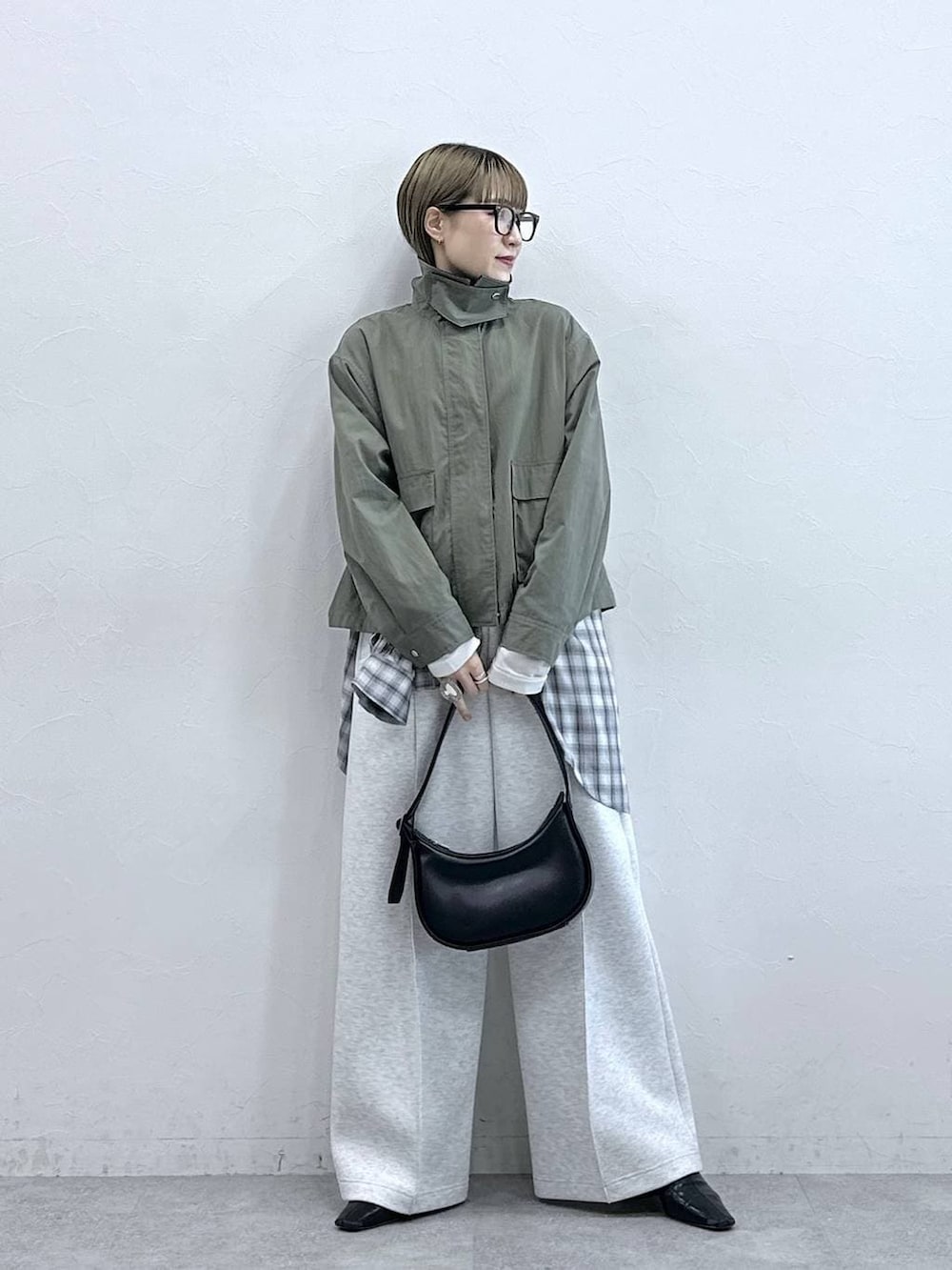 ホワイト系のスウェットパンツ、ブラック系のショルダーバッグ、グリーン系のブルゾンを着用したレディースの冬コーディネートの3枚目の写真