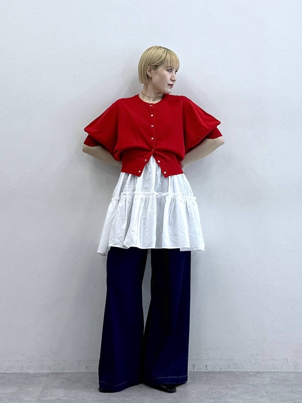 ホワイト系のチュニック、ブルー系のデニムパンツ、レッド系のカーディガン/ボレロを着用したレディースの春コーディネートの3枚目の写真