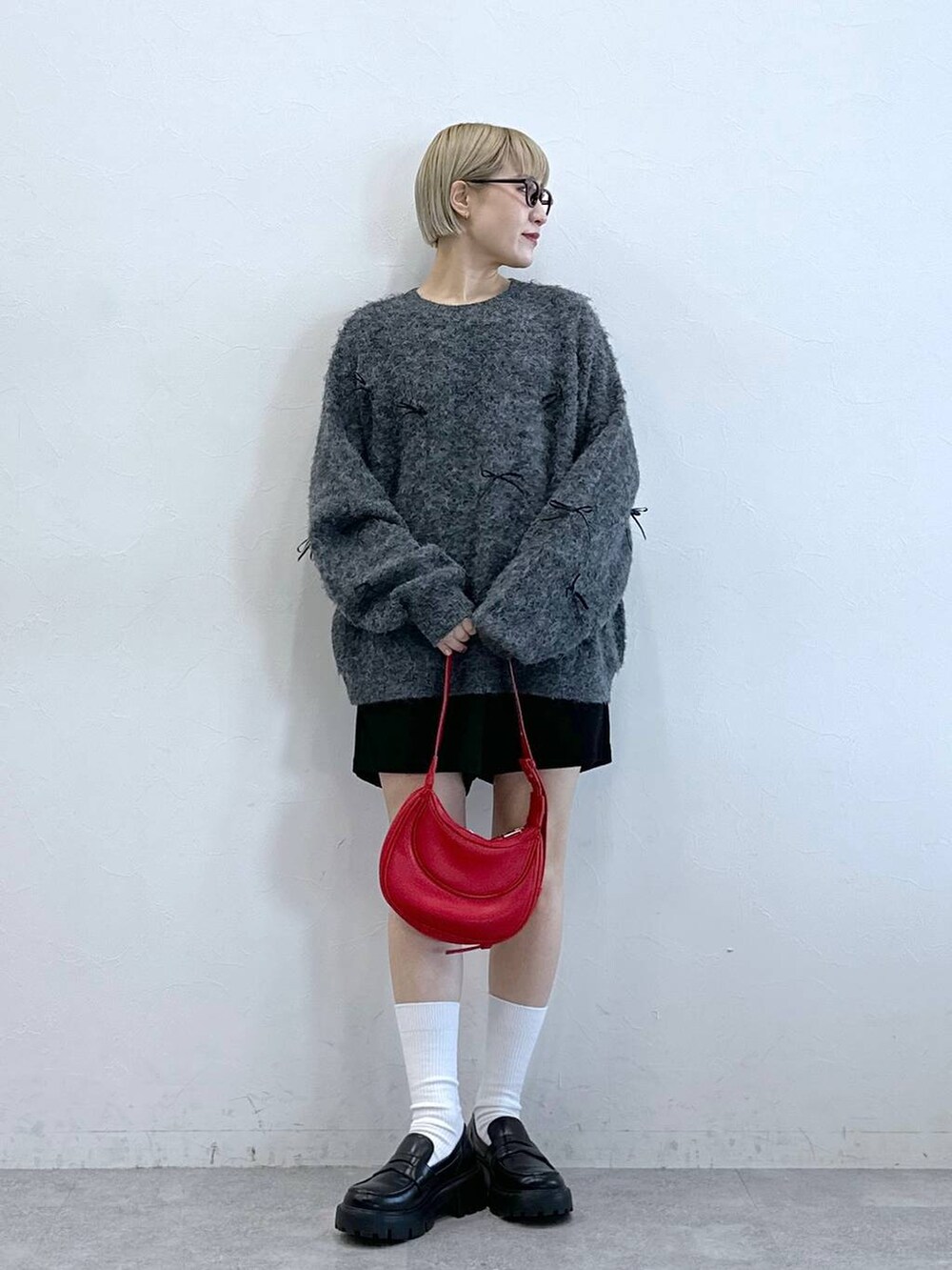 ブラック系のチノパンツ、レッド系のショルダーバッグ、グレー系のニット/セーターを着用したレディースの冬コーディネートの2枚目の写真