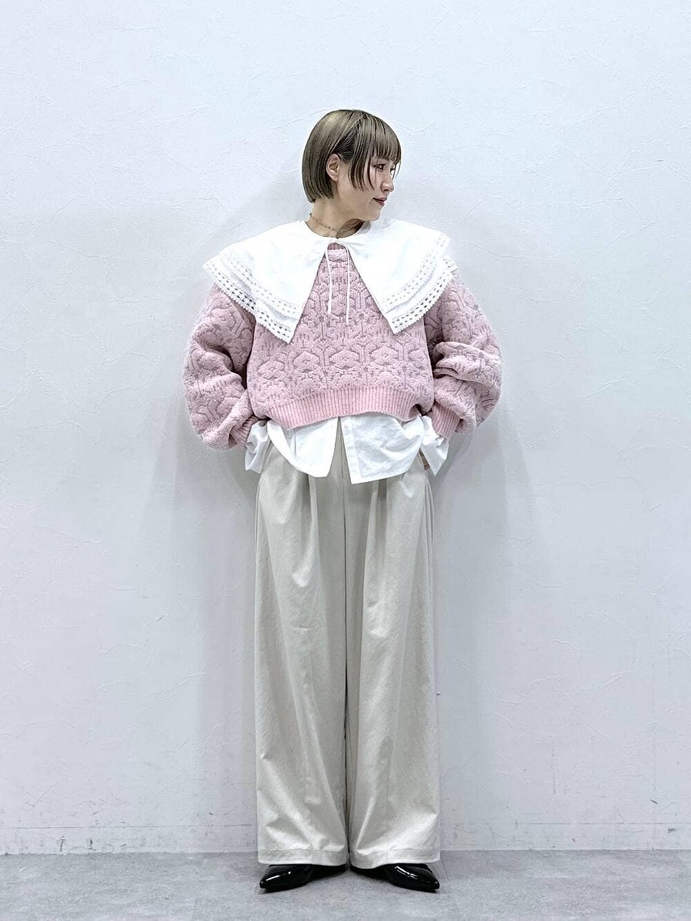 ホワイト系のチノパンツ、ホワイト系のシャツ/ブラウス、ピンク系のニット/セーターを着用したレディースの冬コーディネートの2枚目の写真