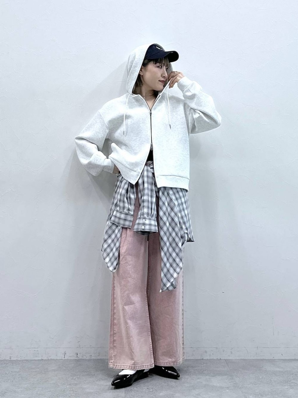 ブラック系のパンプス、ホワイト系のパーカー、ピンク系のデニムパンツを着用したレディースの冬コーディネートの2枚目の写真