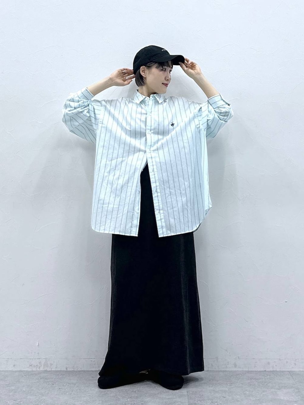 グリーン系のシャツ/ブラウス、ブラック系のモカシン/デッキシューズ、ブラック系のスカートを着用したレディースの春コーディネートの2枚目の写真