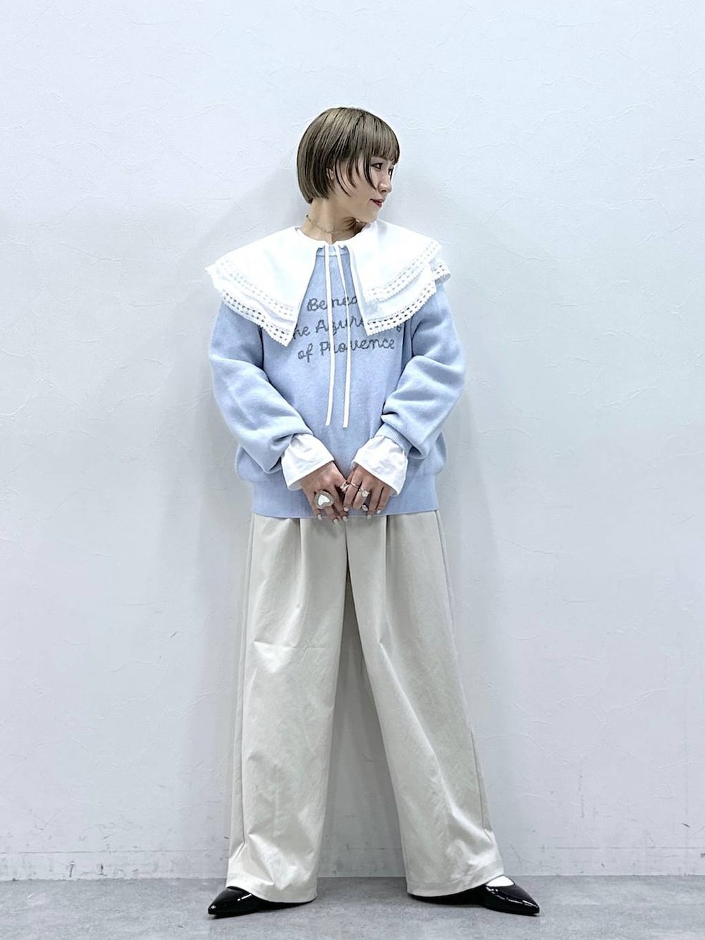 ホワイト系のチノパンツ、ホワイト系のシャツ/ブラウス、ブルー系のニット/セーターを着用したレディースの冬コーディネートの2枚目の写真