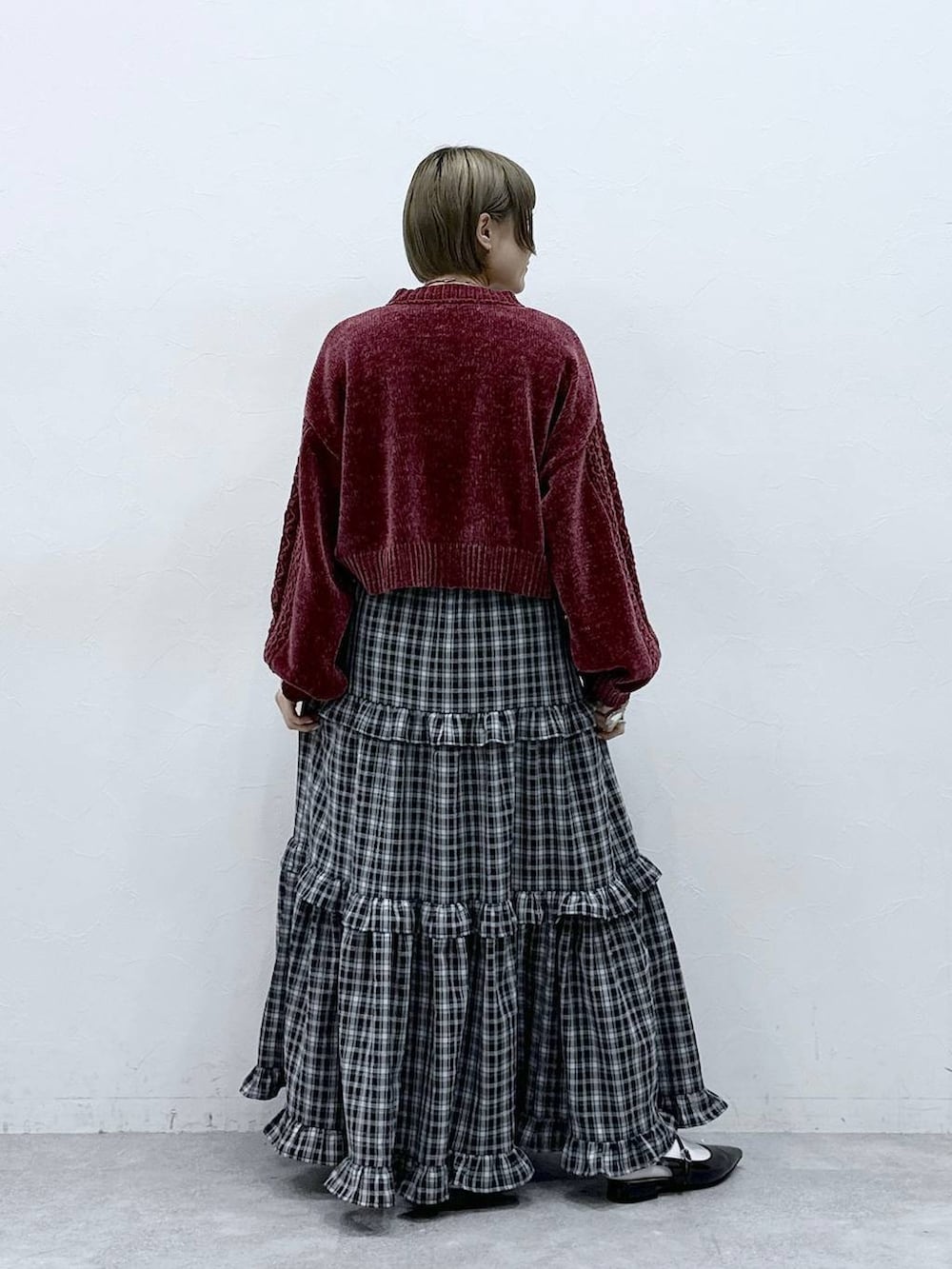 レッド系のニット/セーター、ブラック系のスカート、ブラック系のパンプスを着用したレディースの冬コーディネートの5枚目の写真