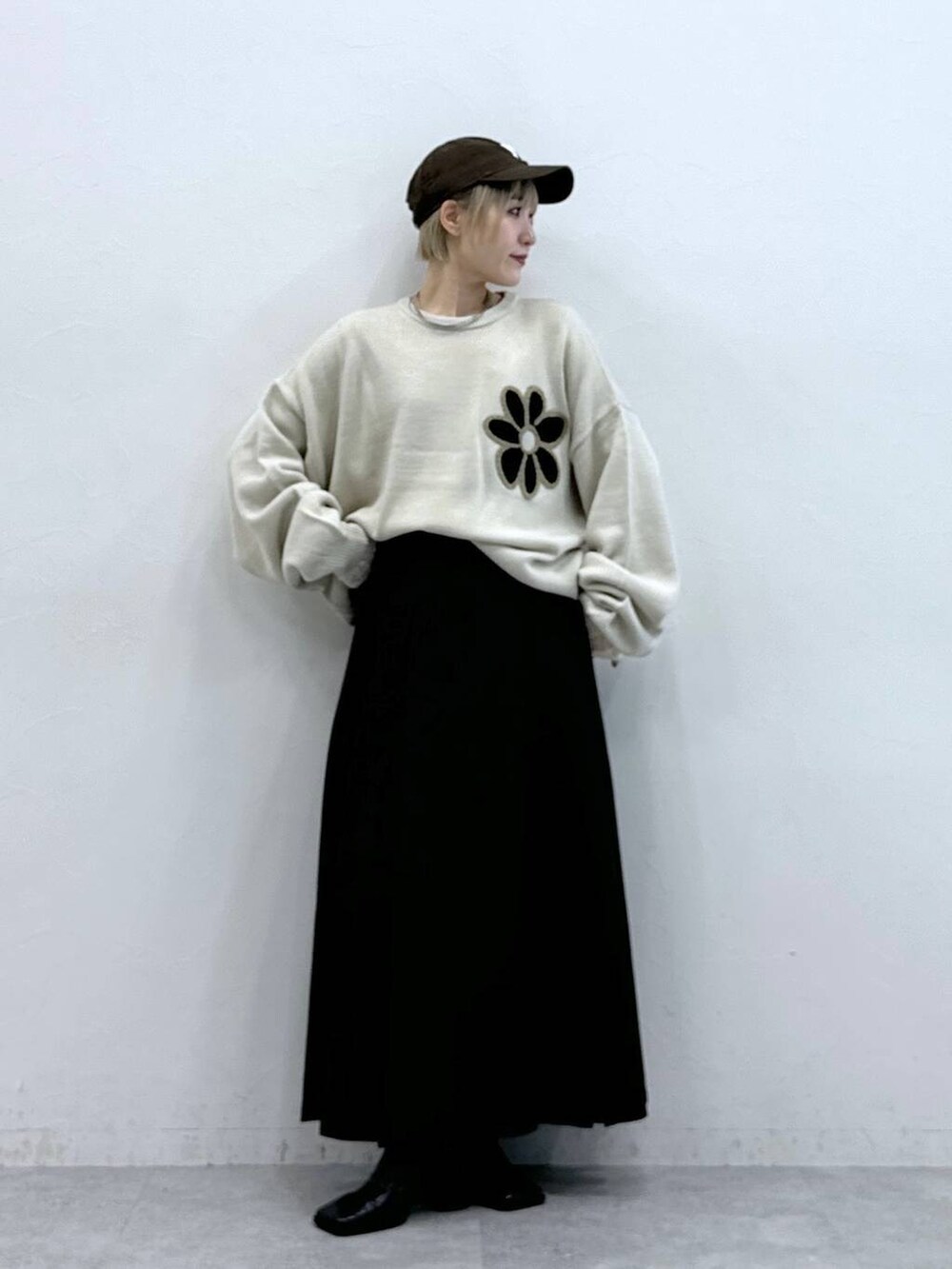 ホワイト系のニット/セーター、ブラウン系のスカート、ホワイト系のTシャツ/カットソーを着用したレディースの秋コーディネートの2枚目の写真