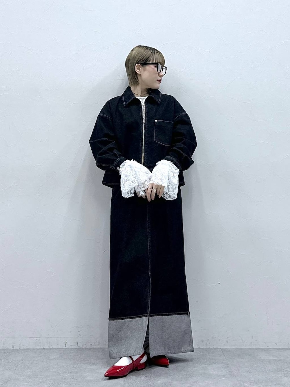 レッド系のパンプス、ブラック系のデニムジャケット、ブラック系のデニムスカートを着用したレディースの冬コーディネートの2枚目の写真