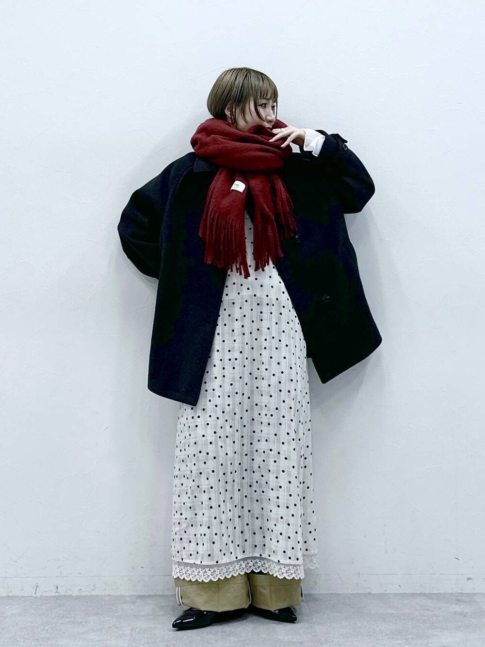 ブラック系のパンプス、ブラック系のステンカラーコート、ベージュ系のチノパンツを着用したレディースの冬コーディネートの3枚目の写真