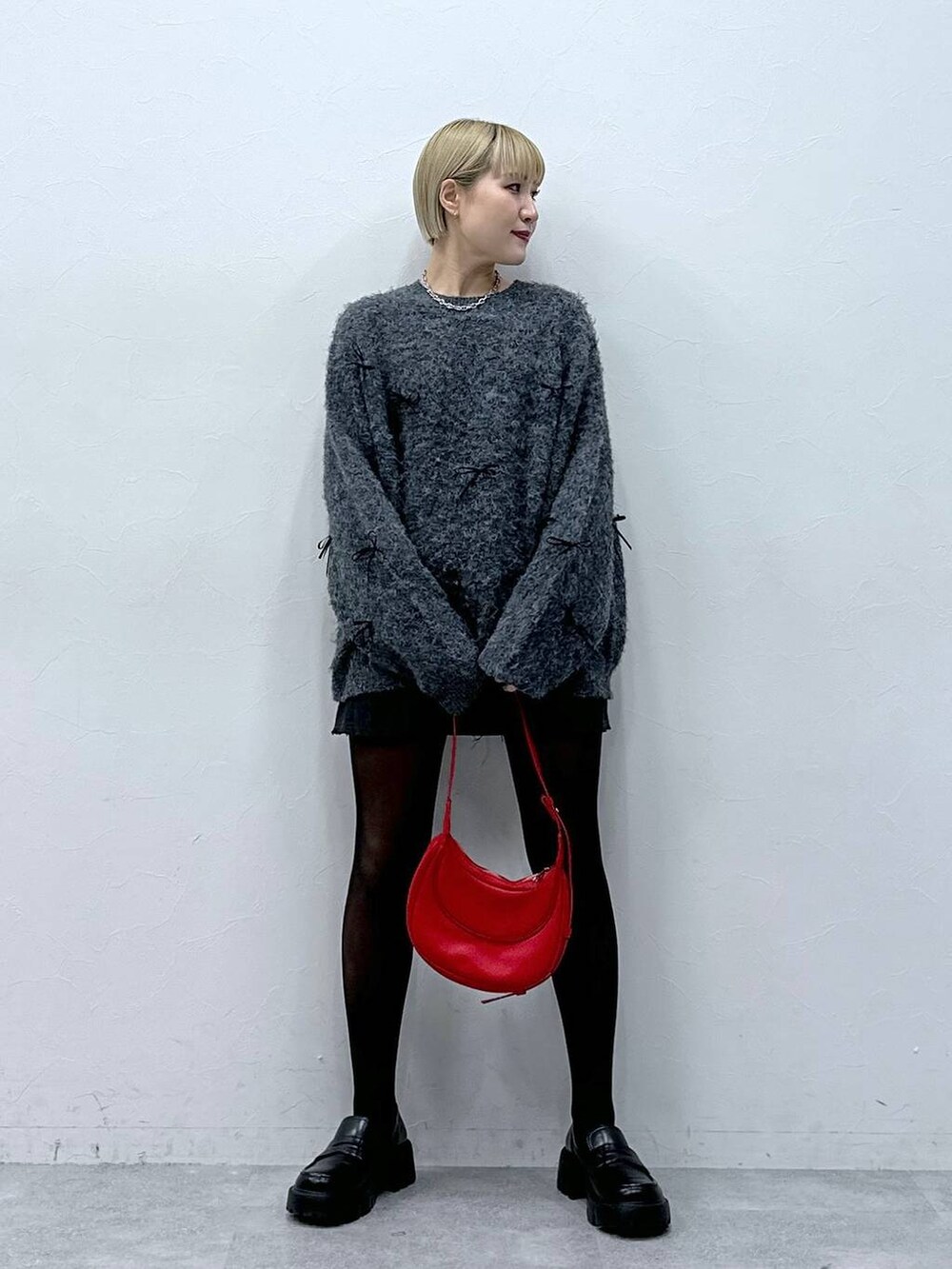 グレー系のスカート、レッド系のショルダーバッグ、グレー系のニット/セーターを着用したレディースの冬コーディネートの5枚目の写真