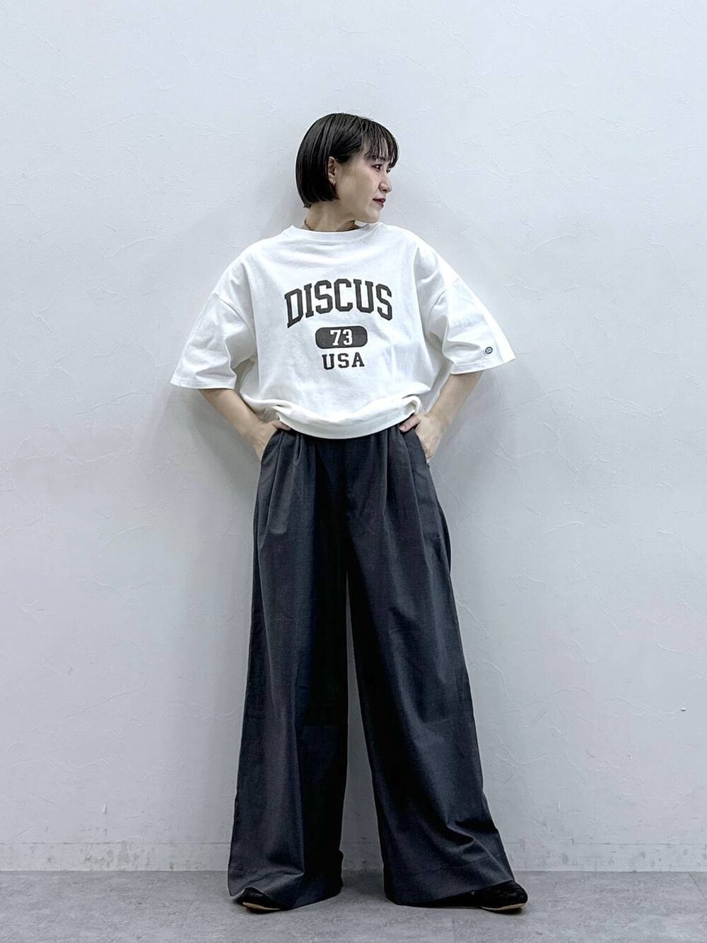 ホワイト系のTシャツ/カットソー、グレー系のスラックスを着用したレディースの春コーディネートの4枚目の写真