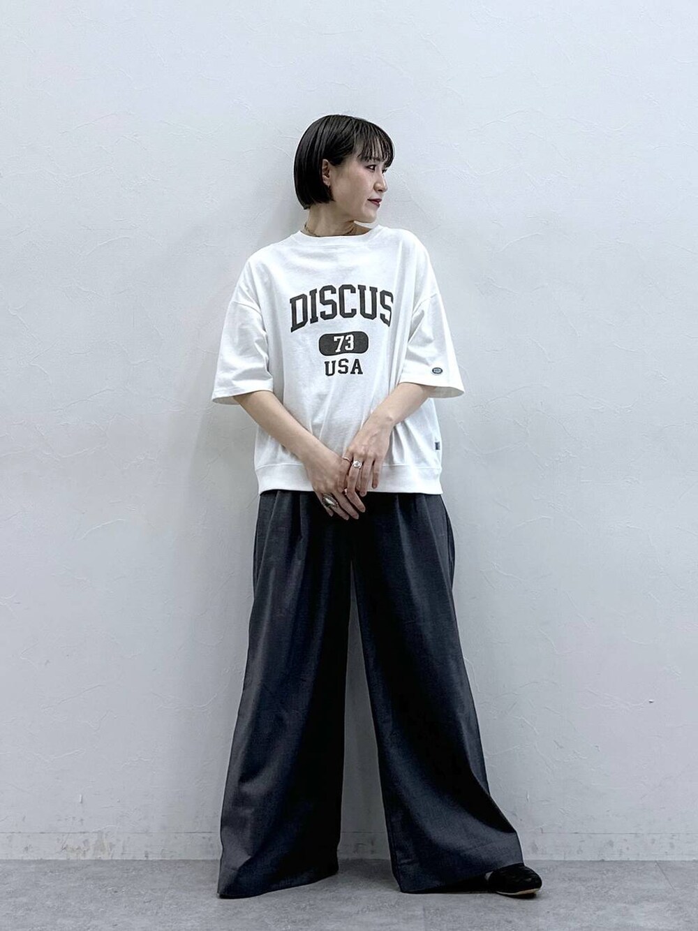 ホワイト系のTシャツ/カットソー、グレー系のスラックスを着用したレディースの春コーディネートの3枚目の写真