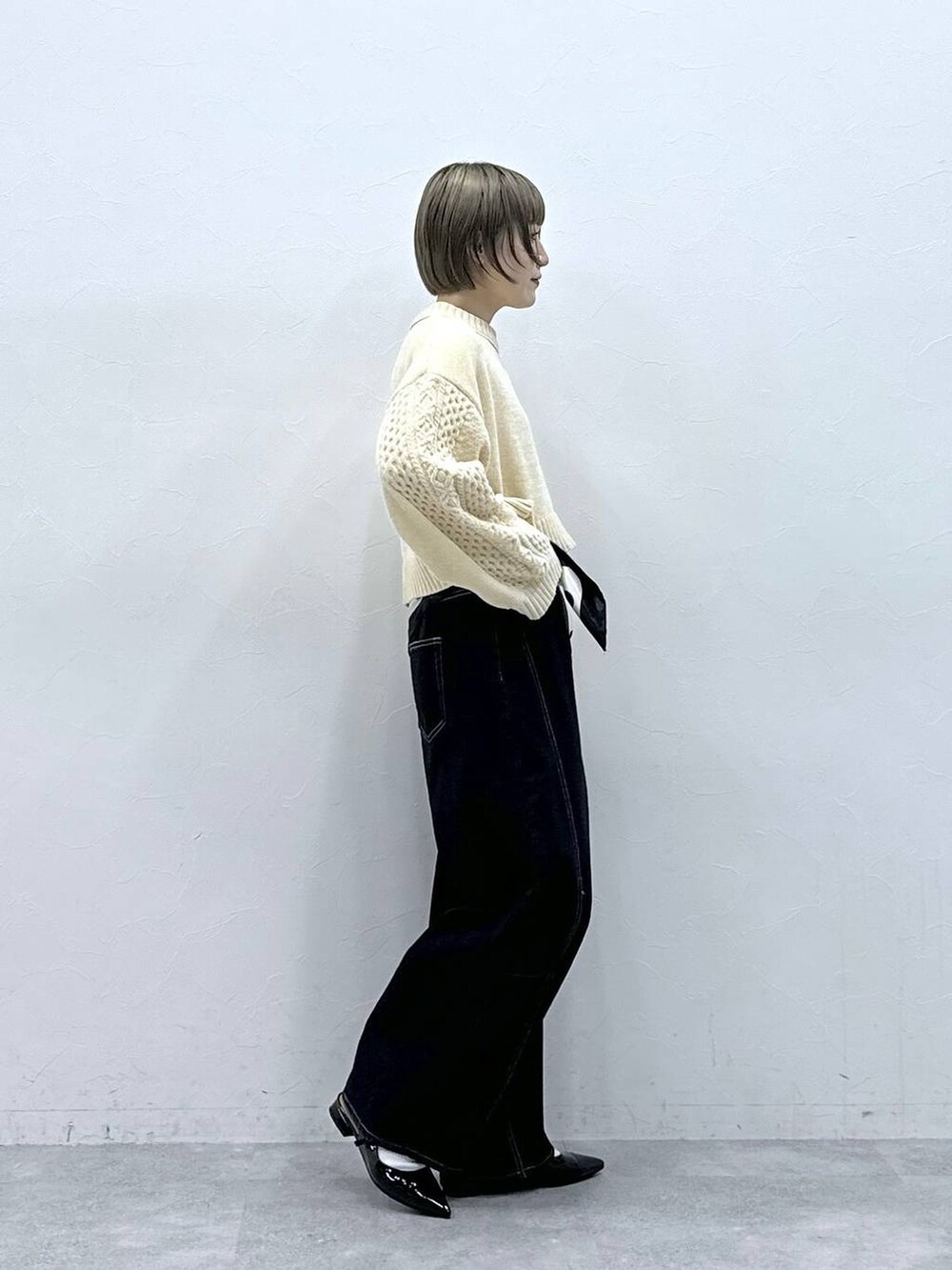 ホワイト系のニット/セーター、ブラック系のパンプス、ブラック系のデニムパンツを着用したレディースの冬コーディネートの4枚目の写真