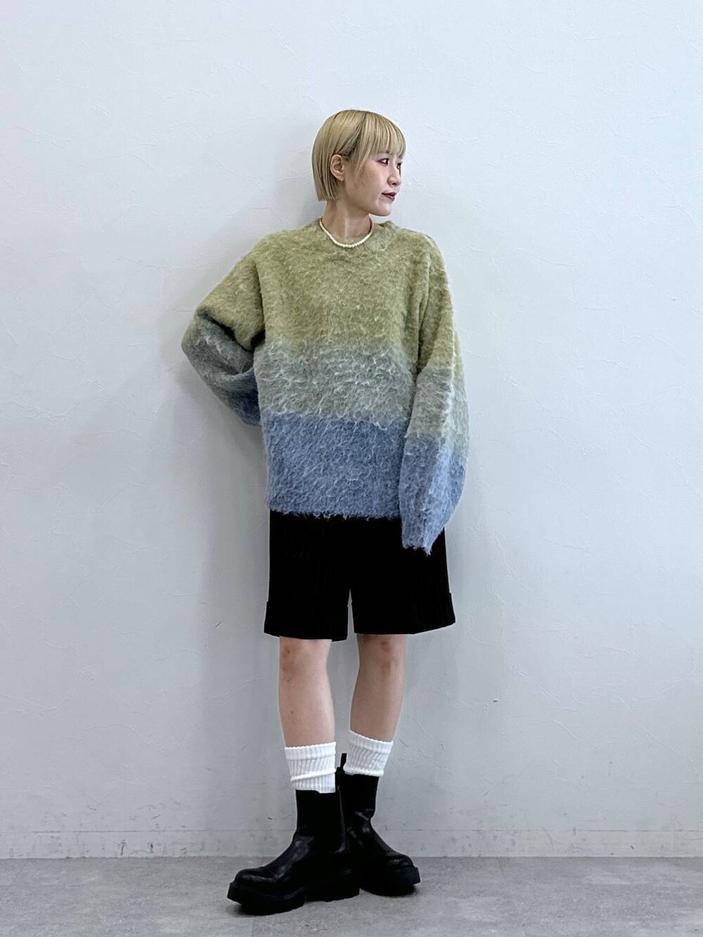 ブラウン系のスラックス、ブラック系のブーツ、イエロー系のニット/セーターを着用したレディースの秋コーディネートの4枚目の写真