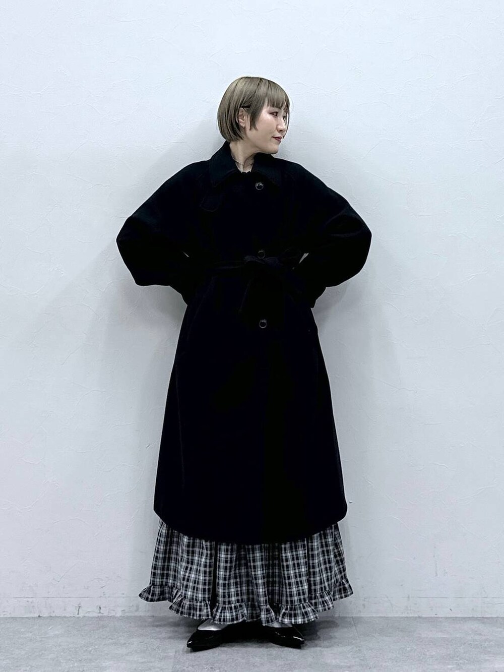 ブラック系のステンカラーコート、ブラック系のスカート、ブラック系のパンプスを着用したレディースの冬コーディネートの3枚目の写真