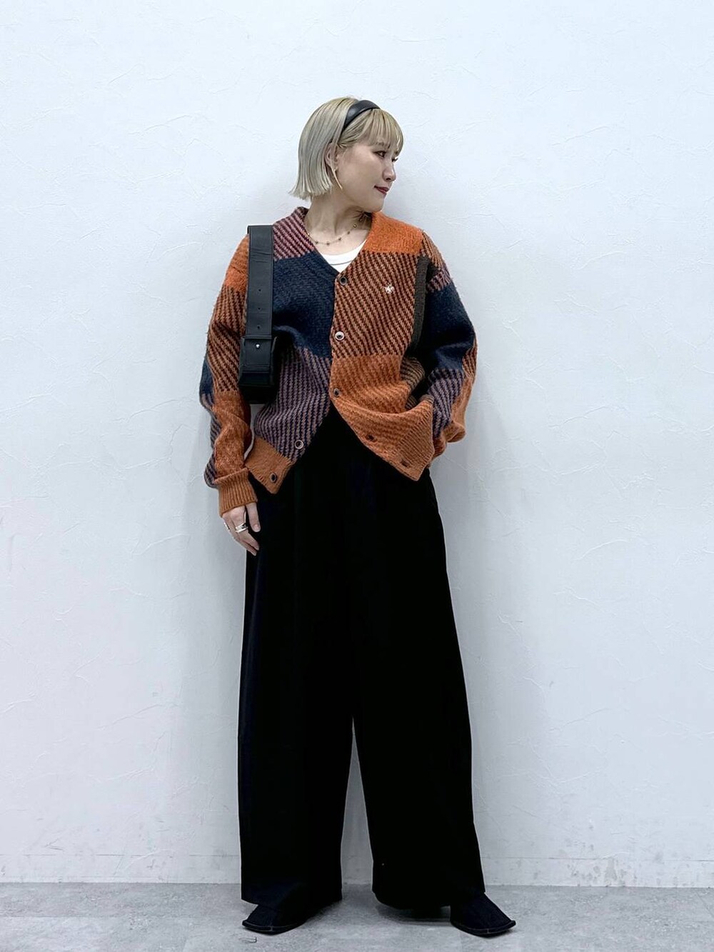 イエロー系のカーディガン/ボレロ、ブラック系のスラックス、ブラック系のショルダーバッグを着用したレディースの秋コーディネートの2枚目の写真