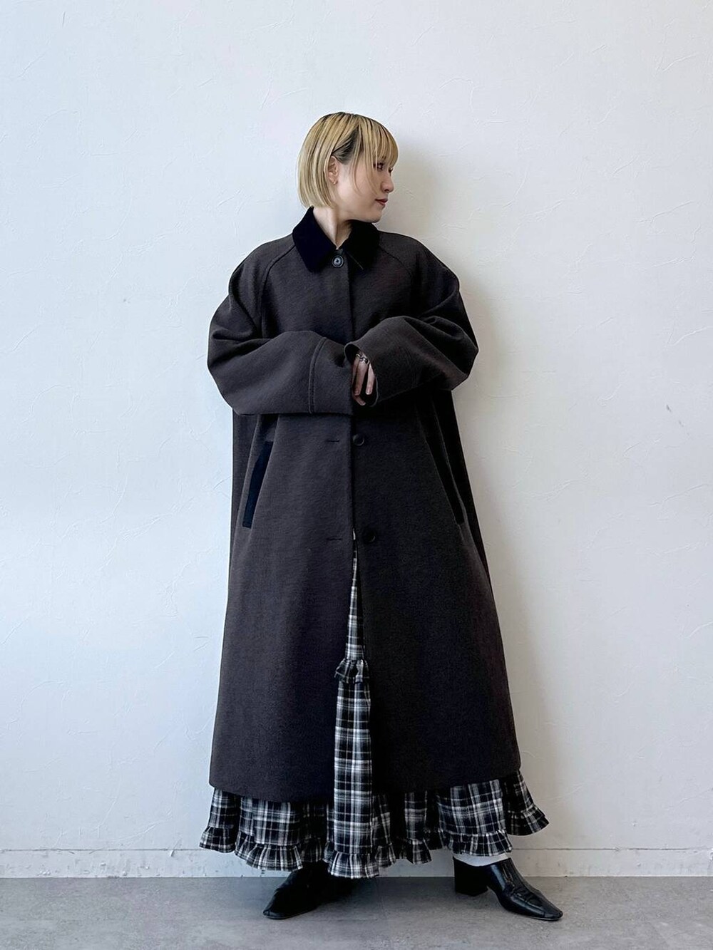ブラウン系のステンカラーコート、ブラック系のスカートを着用したレディースの冬コーディネートの2枚目の写真