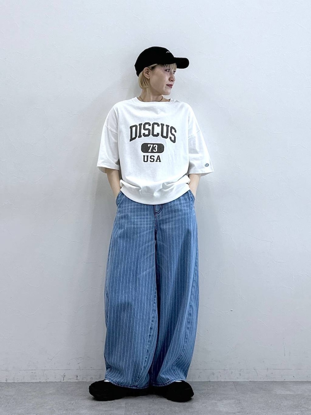 ホワイト系のTシャツ/カットソー、ブラック系のサンダル、ブルー系のデニムパンツを着用したレディースの春コーディネートの2枚目の写真
