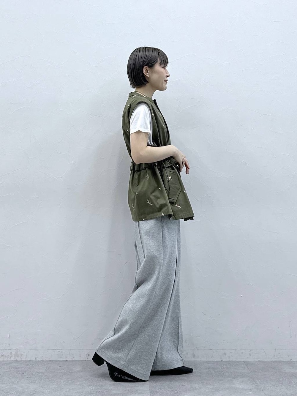 グレー系のスウェットパンツ、ホワイト系のTシャツ/カットソー、グリーン系のベストを着用したレディースの春コーディネートの4枚目の写真