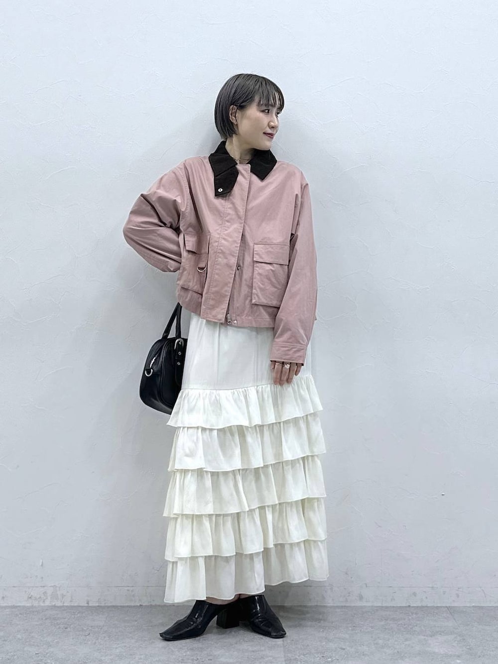 ピンク系のブルゾン、ホワイト系のスカートを着用したレディースの春コーディネートの3枚目の写真