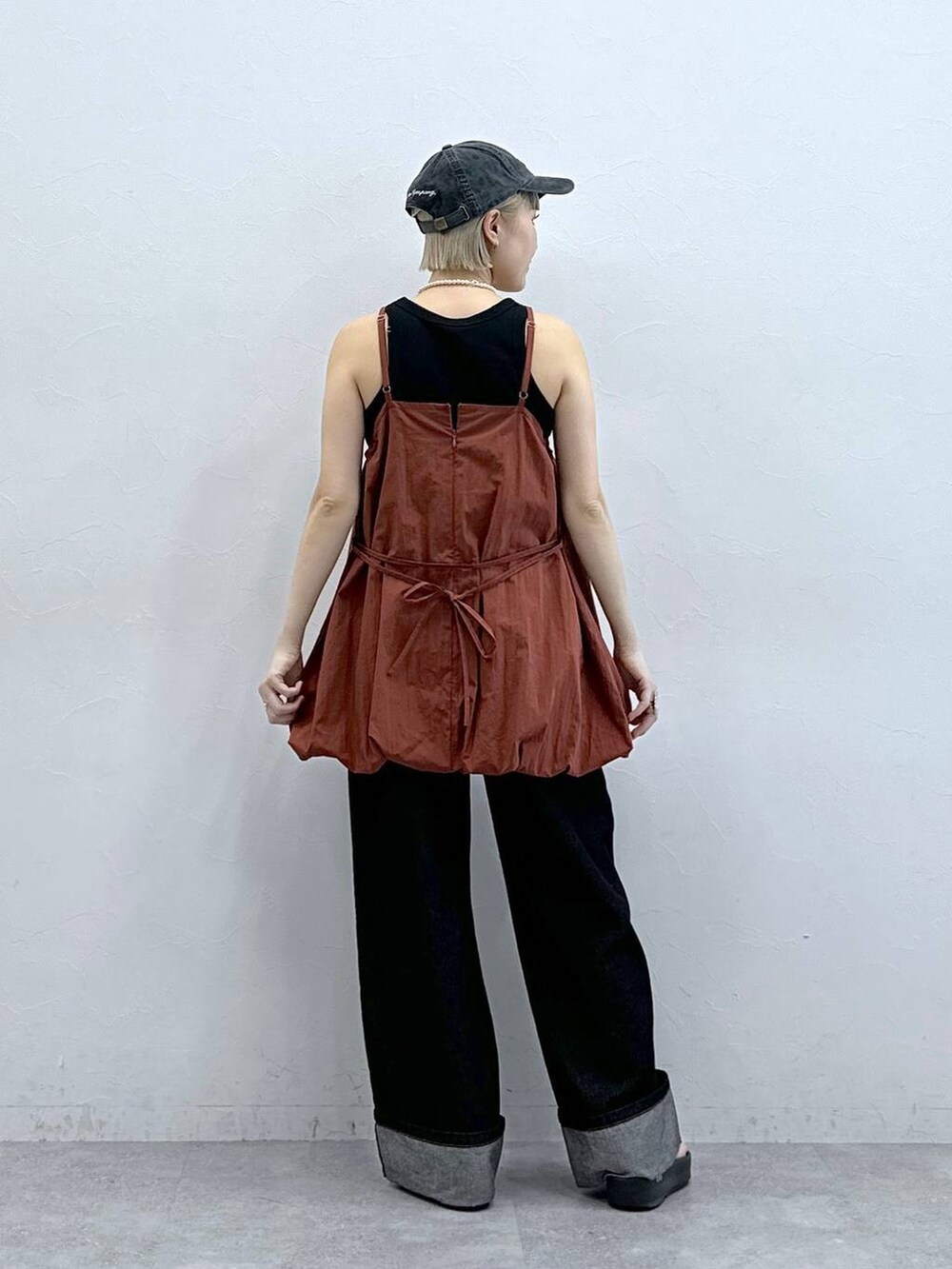 ブラウン系のワンピース、ブラック系のデニムパンツ、ブラック系のキャップを着用したレディースの夏コーディネートの5枚目の写真