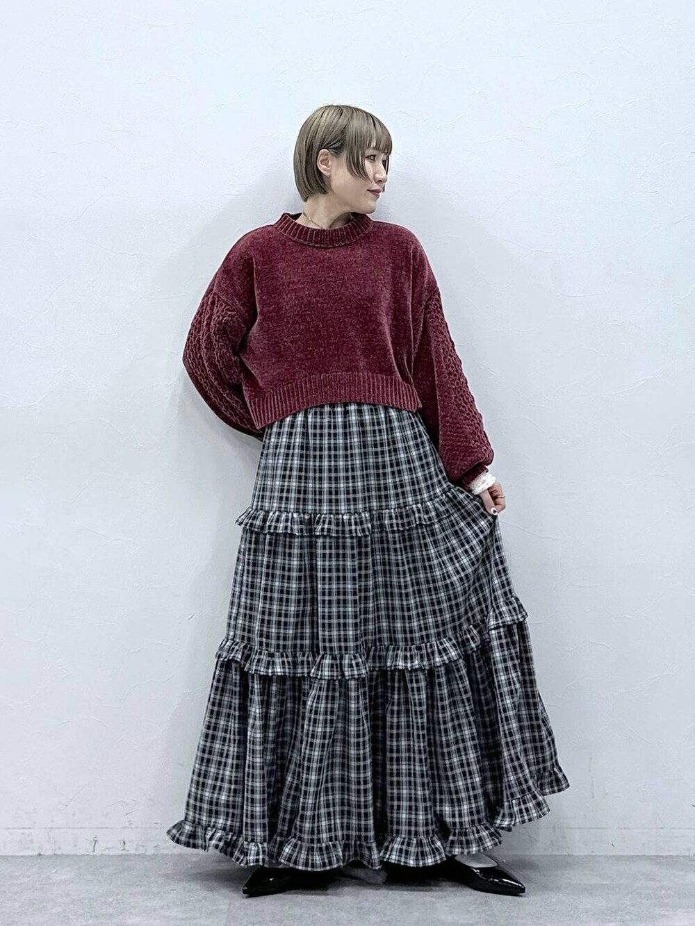 レッド系のニット/セーター、ブラック系のスカート、ブラック系のパンプスを着用したレディースの冬コーディネートの2枚目の写真