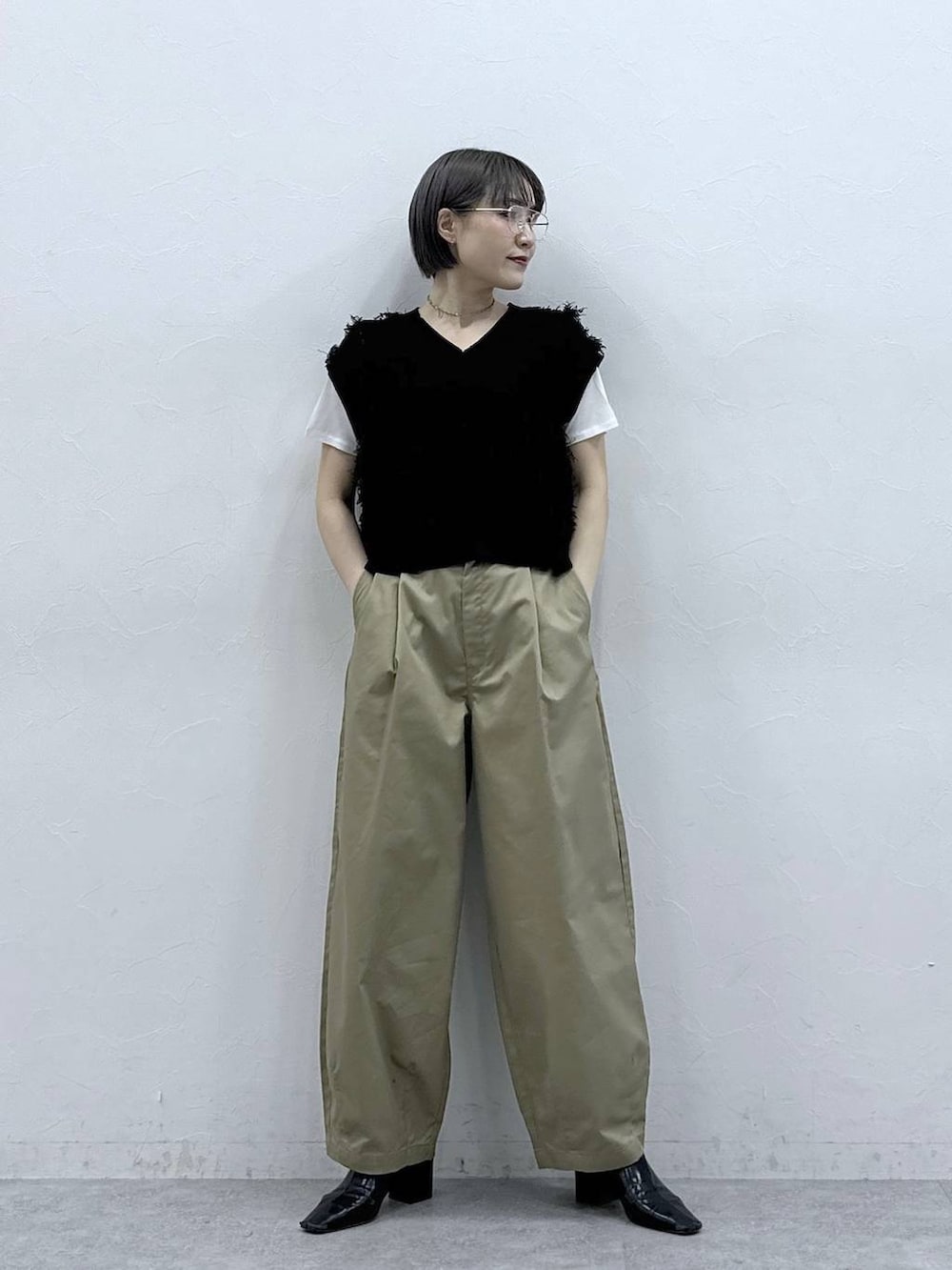 ベージュ系のチノパンツ、ホワイト系のTシャツ/カットソー、ブラック系のベストを着用したレディースの春コーディネートの4枚目の写真
