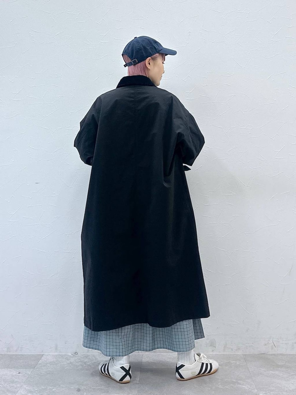 ブラック系のステンカラーコート、ホワイト系のスニーカー、ブルー系のシャツワンピースを着用したレディースの冬コーディネートの3枚目の写真