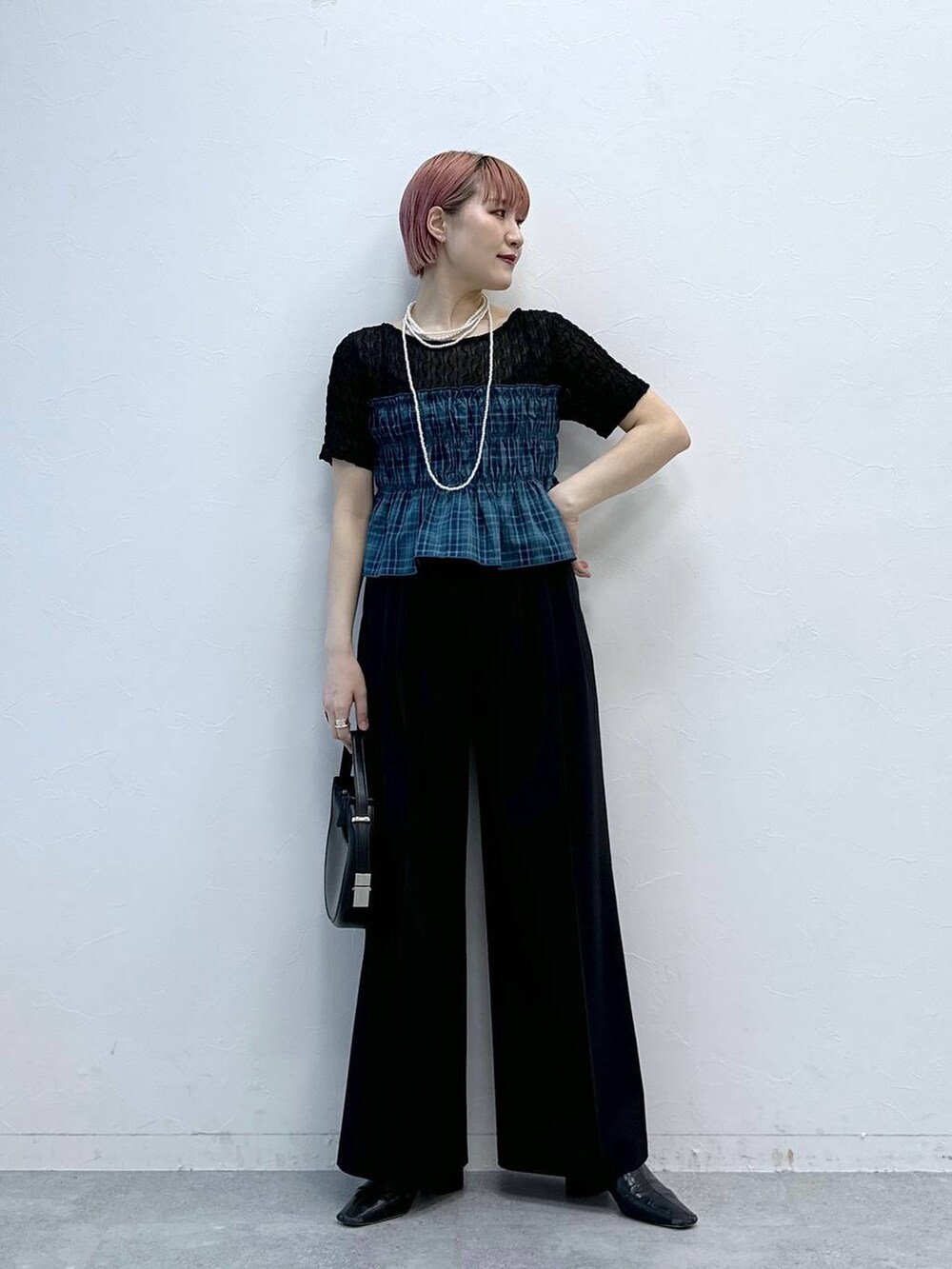 ブラック系のスラックス、ブラック系のTシャツ/カットソーを着用したレディースの春コーディネートの2枚目の写真