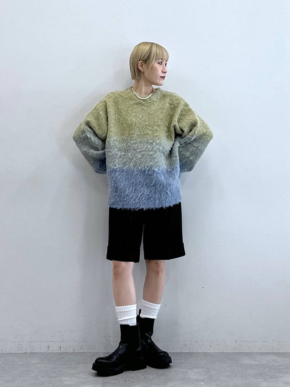 ブラウン系のスラックス、ブラック系のブーツ、イエロー系のニット/セーターを着用したレディースの秋コーディネートの3枚目の写真