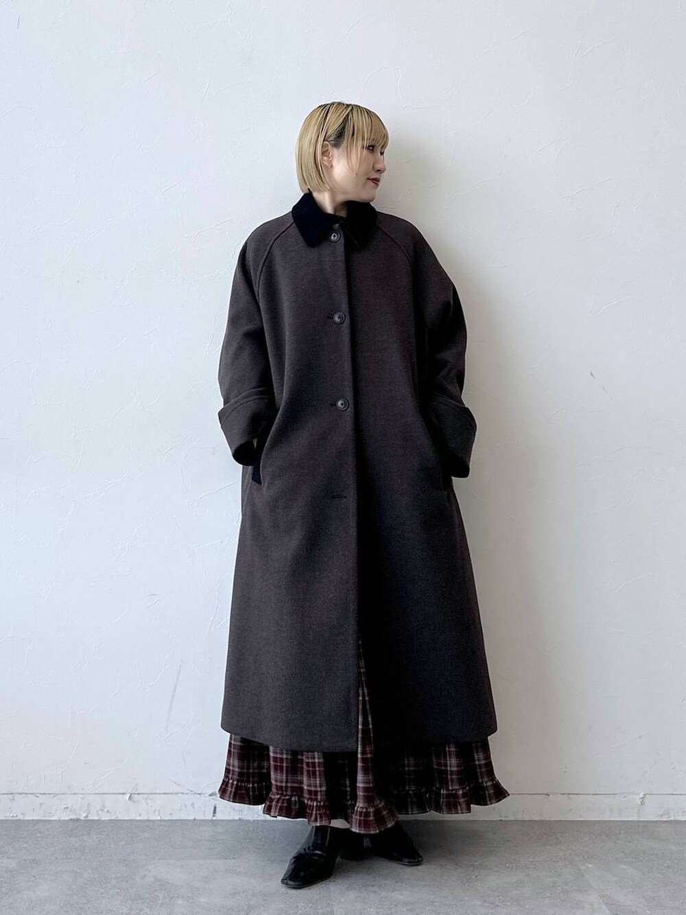 ブラウン系のステンカラーコート、レッド系のスカートを着用したレディースの秋コーディネートの3枚目の写真