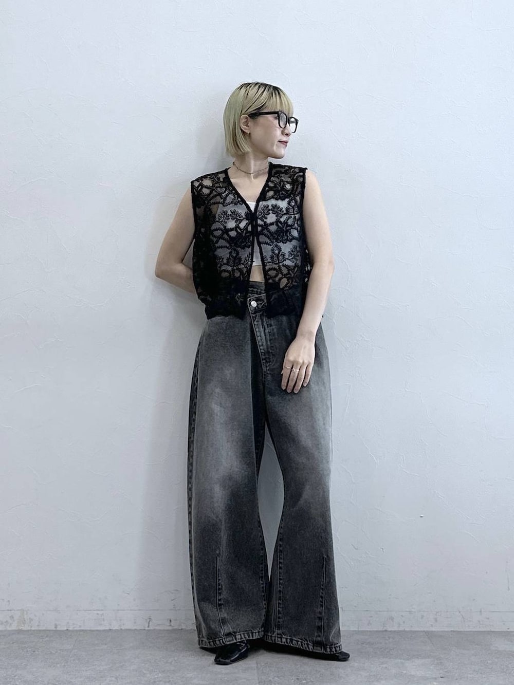 グレー系のデニムパンツ、ブラック系のベスト、ホワイト系のブラジャーを着用したレディースの夏コーディネートの4枚目の写真