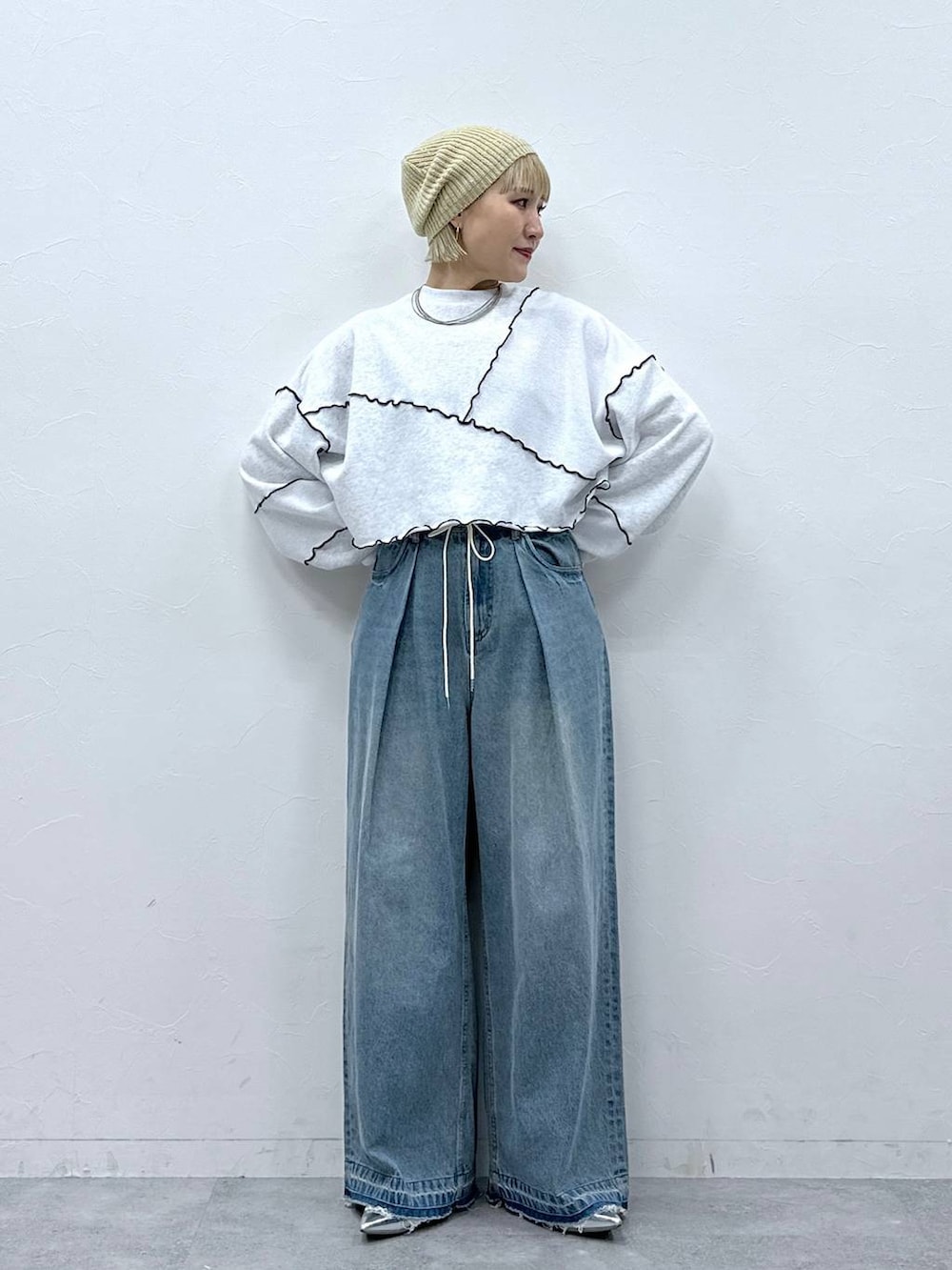 シルバー系のパンプス、ブルー系のデニムパンツ、ホワイト系のスウェットを着用したレディースの秋コーディネートの2枚目の写真