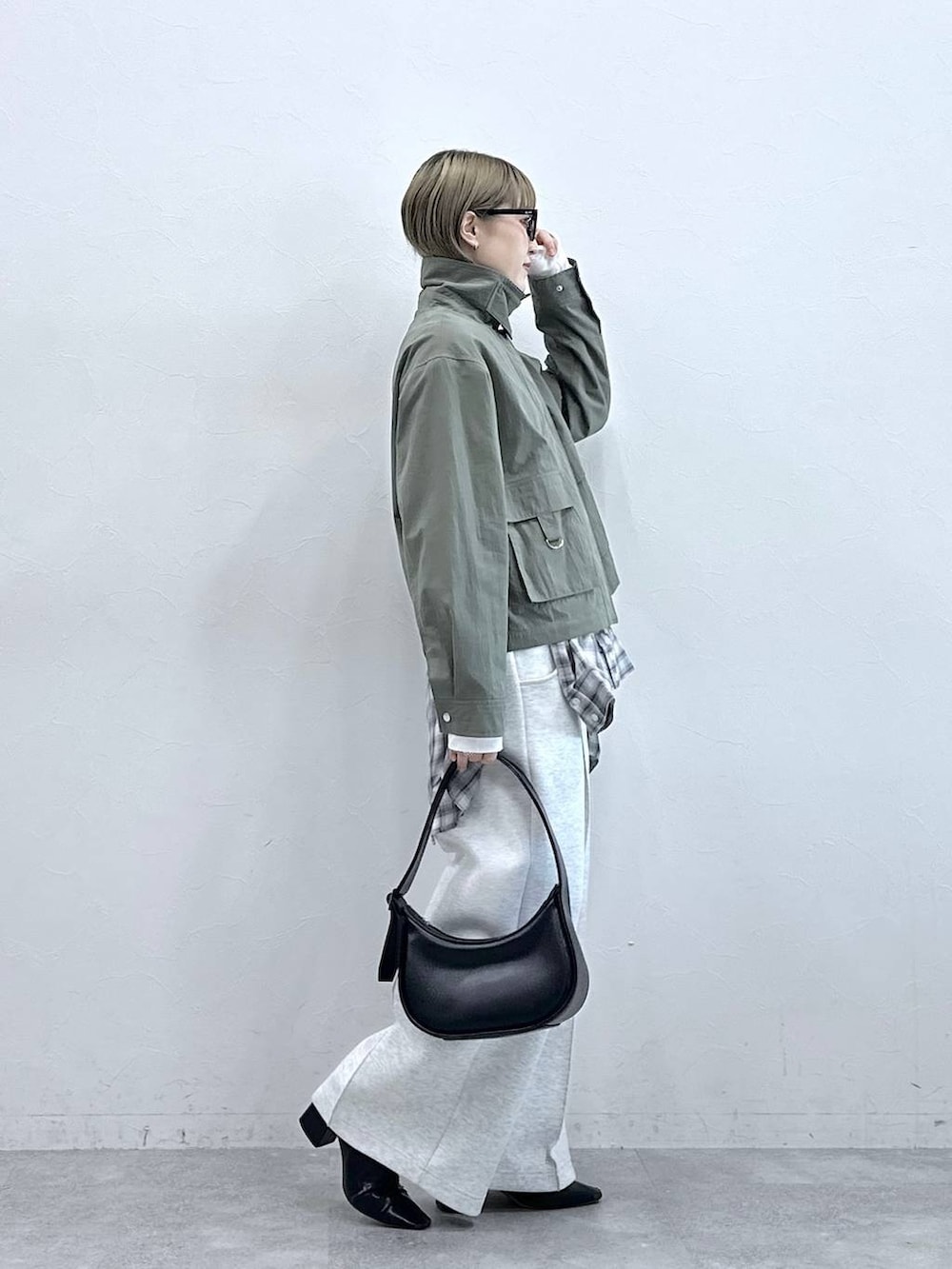 ホワイト系のスウェットパンツ、ブラック系のショルダーバッグ、グリーン系のブルゾンを着用したレディースの冬コーディネートの5枚目の写真