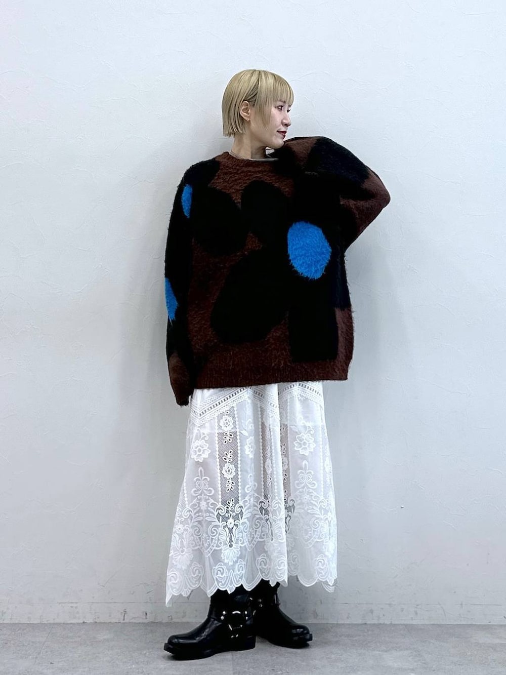 ブラック系のブーツ、ブラウン系のニット/セーター、ホワイト系のスカートを着用したレディースの秋コーディネートの2枚目の写真