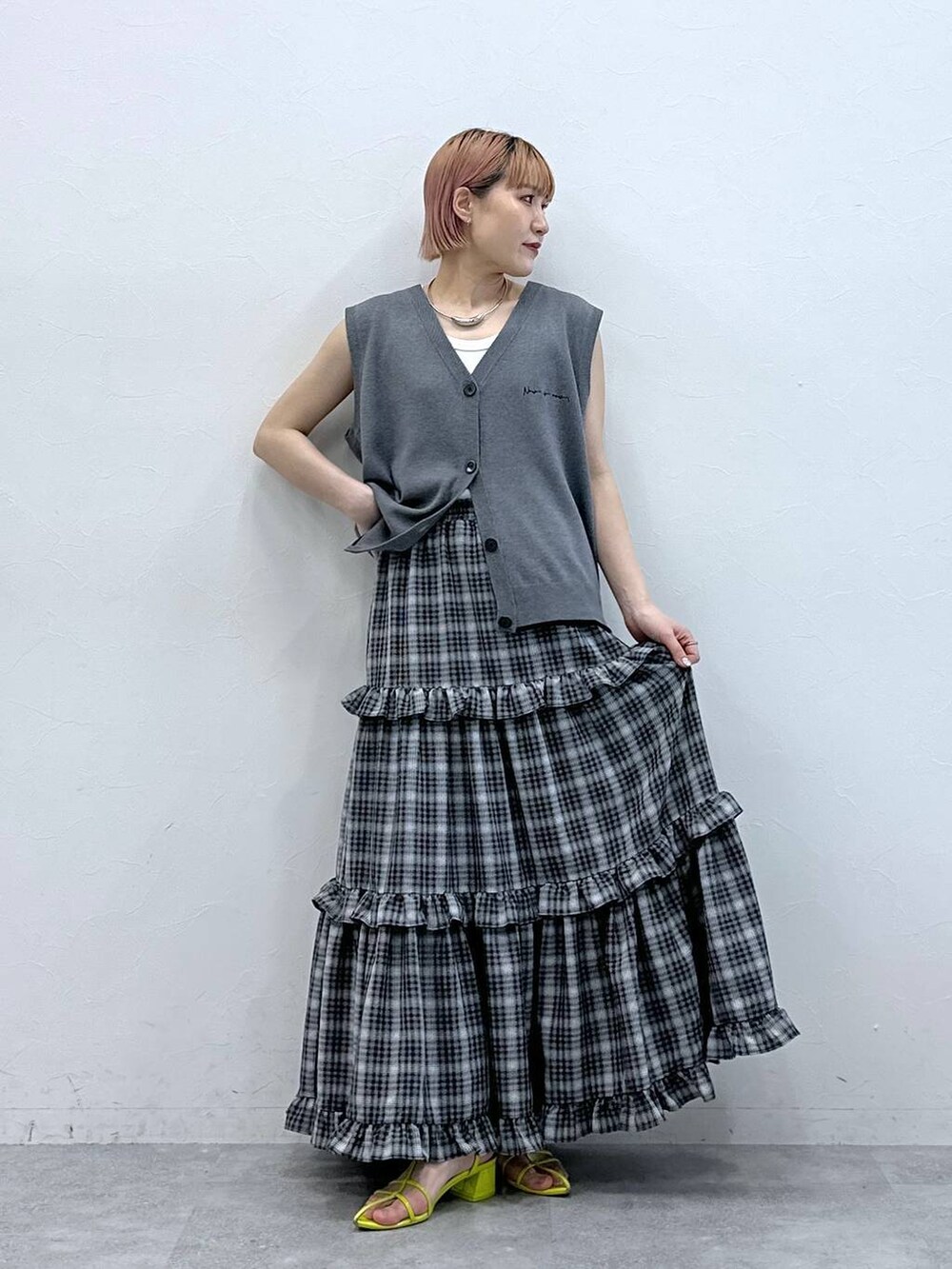 グレー系のベスト、ホワイト系のタンクトップ、ブラック系のスカートを着用したレディースの春コーディネートの2枚目の写真