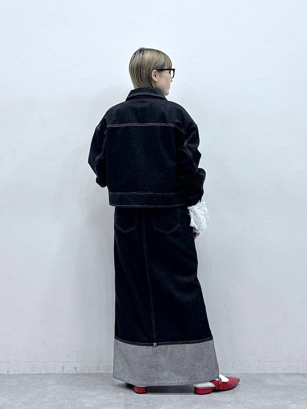 レッド系のパンプス、ブラック系のデニムジャケット、ブラック系のデニムスカートを着用したレディースの冬コーディネートの6枚目の写真