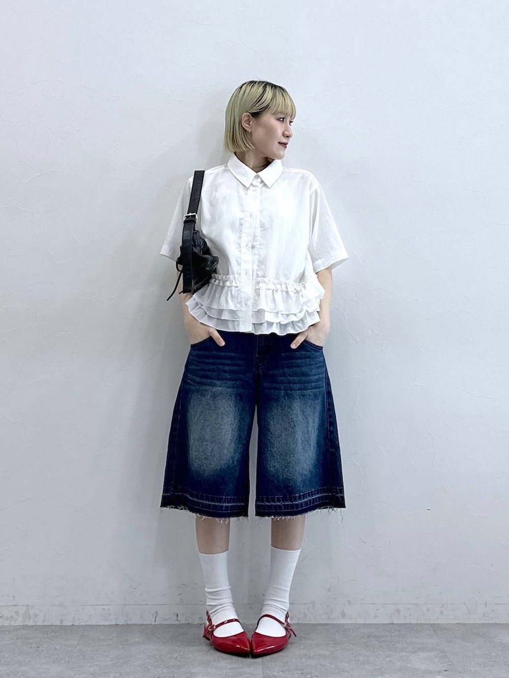 ブルー系のデニムパンツ、ブラック系のショルダーバッグ、レッド系のパンプスを着用したレディースの夏コーディネートの3枚目の写真