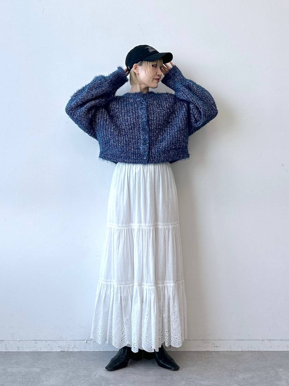 ブルー系のニット/セーター、ホワイト系のスカート、ブラック系のキャップを着用したレディースの秋コーディネートの2枚目の写真