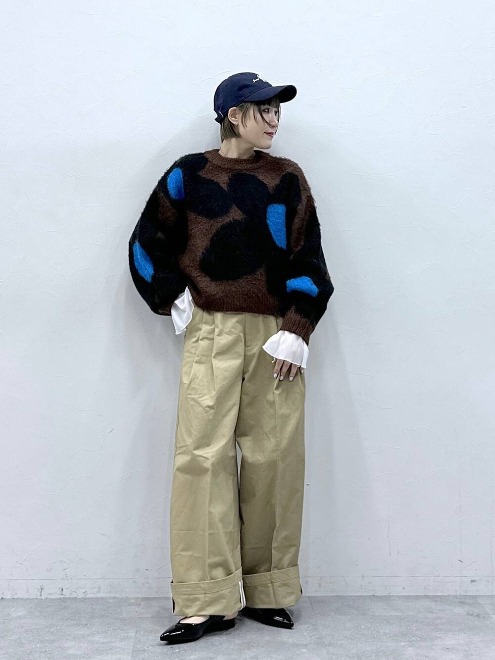 ブラウン系のニット/セーター、ブラック系のパンプス、ベージュ系のチノパンツを着用したレディースの冬コーディネートの2枚目の写真