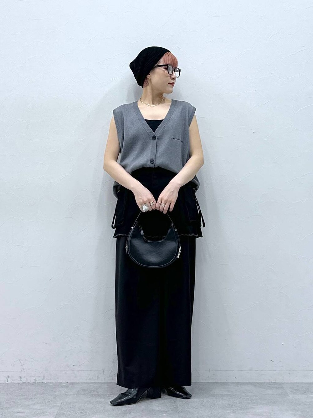 ブラック系のスラックス、ブラック系のスカート、グレー系のベストを着用したレディースの春コーディネートの2枚目の写真