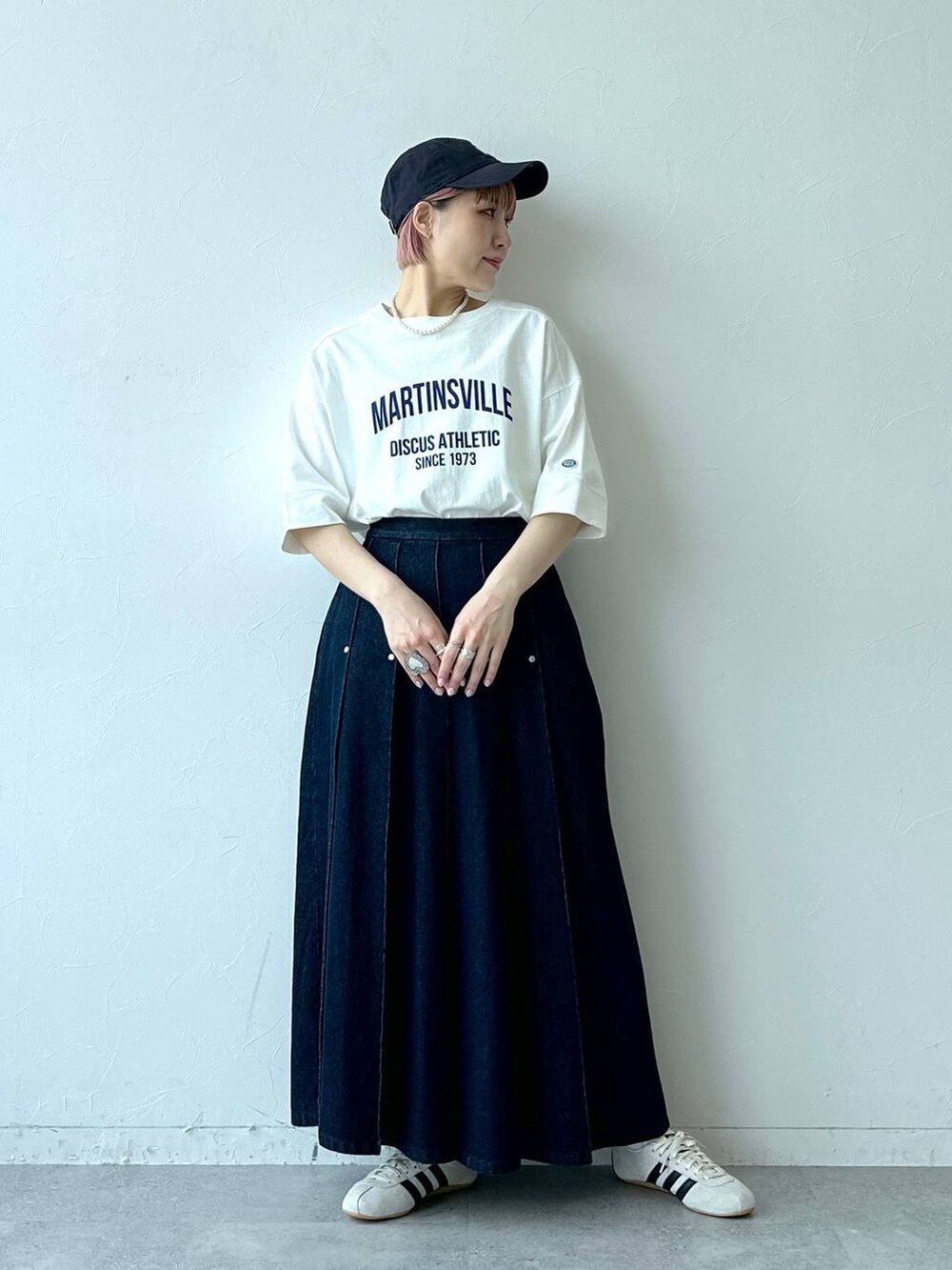 ホワイト系のTシャツ/カットソー、ホワイト系のスニーカー、ブルー系のデニムスカートを着用したレディースの春コーディネートの3枚目の写真