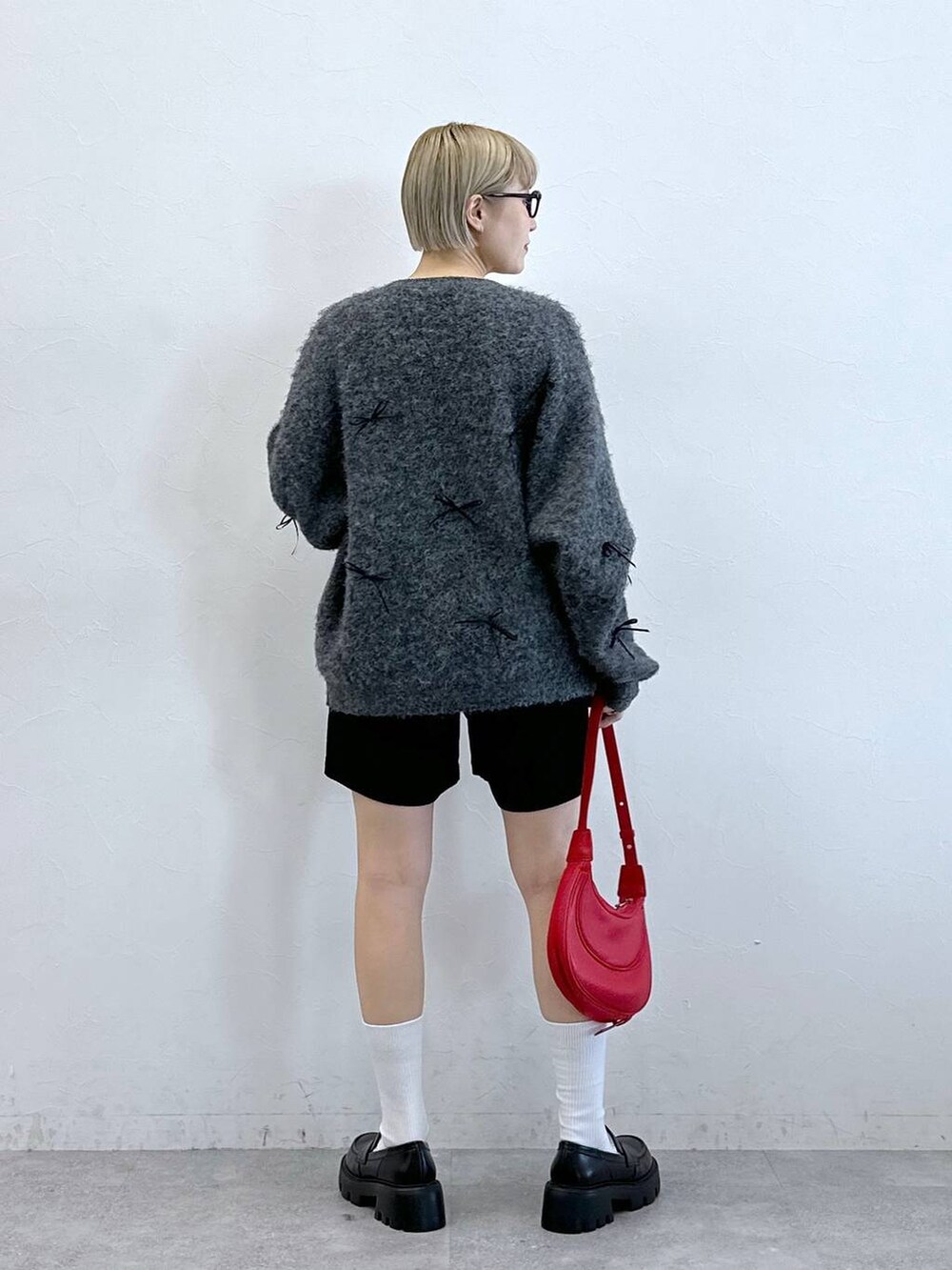 ブラック系のチノパンツ、レッド系のショルダーバッグ、グレー系のニット/セーターを着用したレディースの冬コーディネートの5枚目の写真