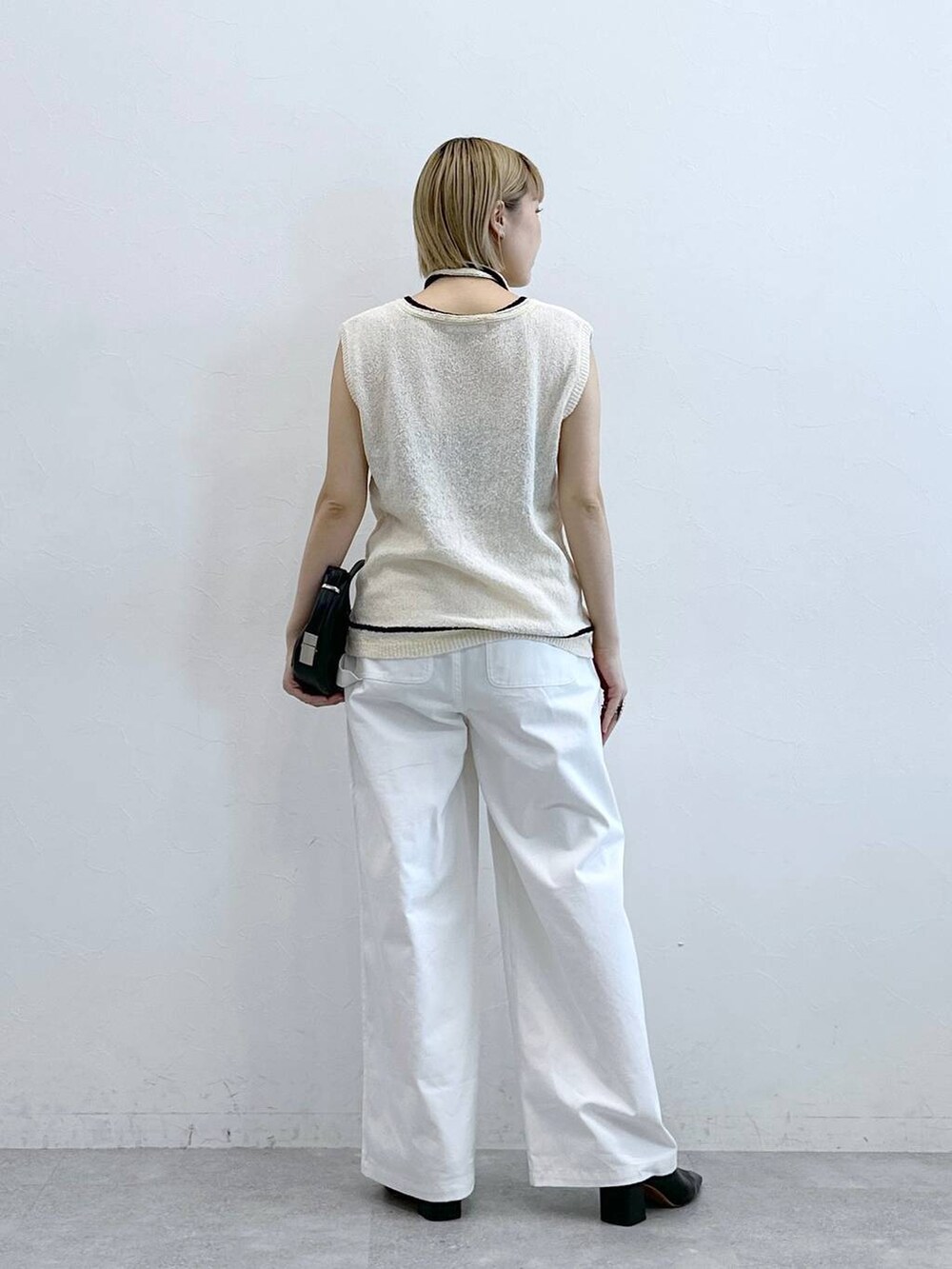 ホワイト系のニット/セーター、ホワイト系のチノパンツを着用したレディースの夏コーディネートの6枚目の写真